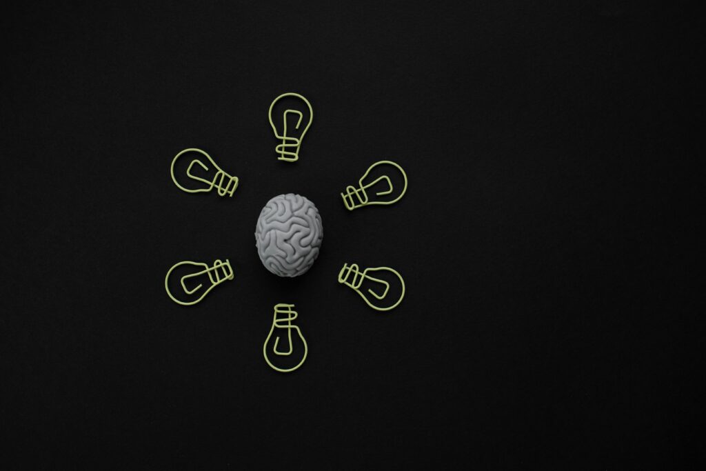 Conceptual photo of a brain surrounded by light bulb clips on black background.